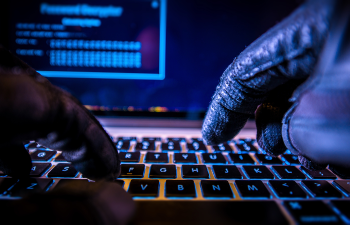 Hands with black gloves typing on a keyboard in a dark room