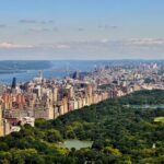 photo of New York City's Central park in the day time from a side view, blue skies, green grass
