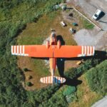 orange plane viewed from the top sitting a field surrounded by grass