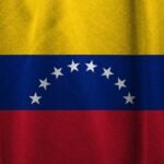The Venezuelan flag, featuring three horizontal stripes of yellow, blue, and red. The blue stripe contains eight white stars arranged in a semi-circle in the center of the flag.