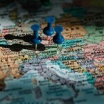A close-up of a map of Europe with three blue push pins marking locations in Austria, Hungary, and Romania. The map shows various European countries, including France, Germany, Slovakia, and Serbia.