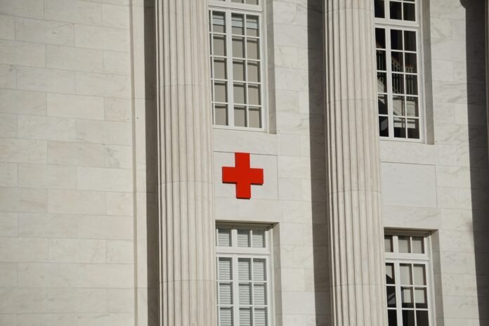 Exterior of a white marble building with a red cross symbol, representing humanitarian aid and emergency medical services.